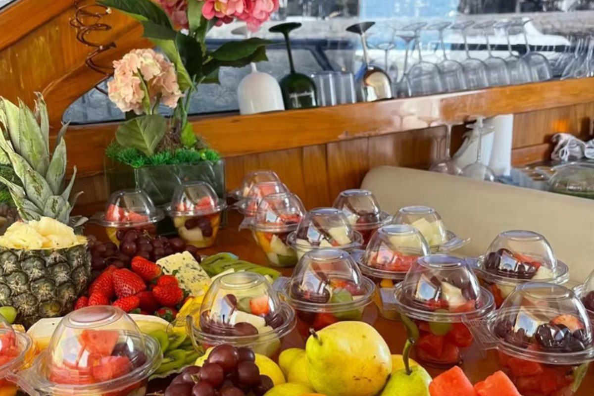 Mesa de frutas com arranjo de flores servida no salão de uma embarcação